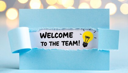Blue torn card revealing “WELCOME TO THE TEAM!” with light bulb and warm bokeh background