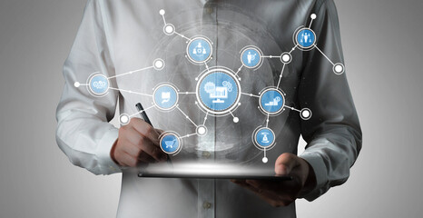 A business professional engages with a digital tablet displaying floating icons that symbolize technology, data connectivity, and innovative solutions in a contemporary workspace. Tessel