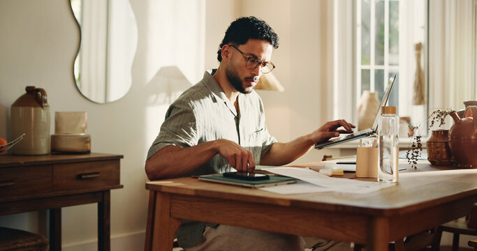 Creative, paperwork and man with laptop, home and search for logo design on web or freelance project. Graphic designer, online and person with tech for digital art, review and serious for remote work