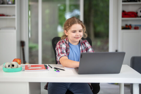 Child study at home with laptop and books. Kid learning in a cozy home classroom. Kid study at classroom. Online learning. Kid thinking concept. Child study at home. Boy doing school homework.