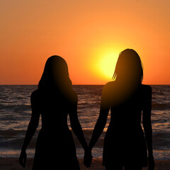 Lesbian couple admiring the sunrise at the seaside