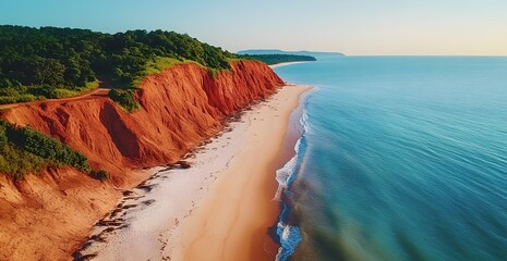 Aerial view of a stunning coastal landscape with dramatic red sandstone cliffs meeting the turquoise ocean and a sandy beach below