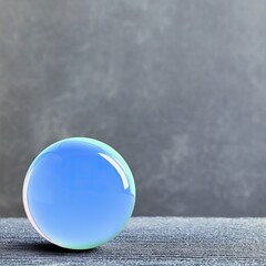 A glossy blue glass sphere sits on a textured surface against a mottled gray background. The sphere reflects light, creating highlights and a sense of depth.