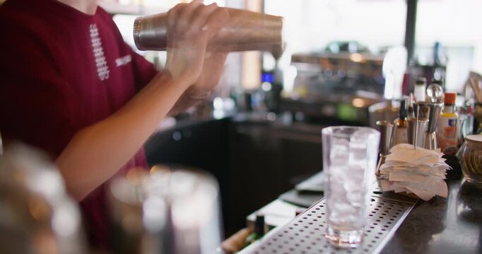 Shaking drink defocused. Bartender work. Professional mixologist preparing cold cocktail in metal container. Cafe counter barkeeper occupation.