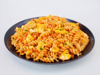 Stir-fried pasta with eggs, on a plate placed on a white background, it looks very delicious and appetizing.