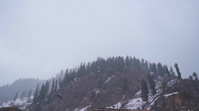 Slow motion shot of snowfall in front of snowy Himalayan mountain peaks during the winter storm as seen from Chandanwari near Pahalgam in Jammu and Kashmir, India. Snowfall in the mountain background.