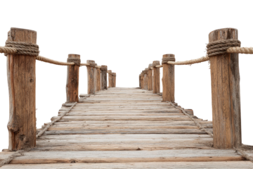 Rustic wooden bridge with rope railings, leading to an unknown destination, against black