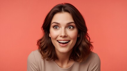 Fototapeta premium Happy surprised woman with excited facial expression. Close-up portrait of joyful young female model with open mouth looking away on coral pink studio background with copy space