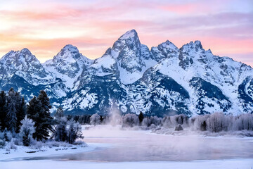 Majestic snow capped teton mountains at sunrise with misty river and frosted trees