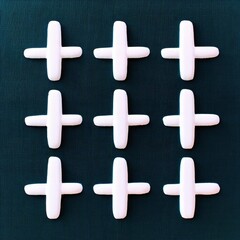 Obraz premium Nine white crosses arranged in a 3x3 grid pattern against a dark green textured background. The crosses are evenly spaced.