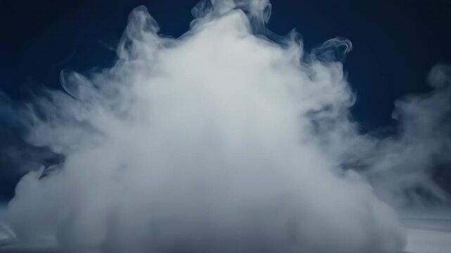 Dense, volumetric white smoke and fog expanding and rolling slowly across a dimly lit, undefined deep blue studio space, creating mystery smooth, space, expanding