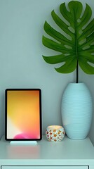 A tablet with a colorful screen sits on a white table next to a vase with a large leaf and a decorative candle. Minimalist, modern interior.
