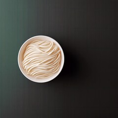 Overhead shot of a bowl filled with udon noodles on a dark green and black background.