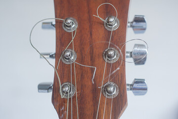 Close-up of a wooden guitar headstock with tuners and strings