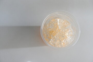 Leftover orange juice with ice in a clear plastic cup.