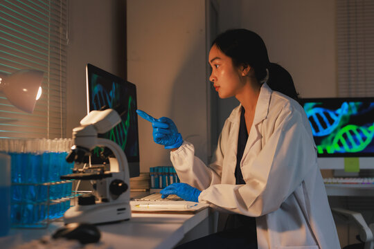 Asian scientist analyzing dna data on computer screen