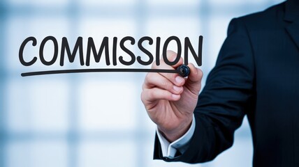 Businessman writes the word commission on a transparent surface with a marker