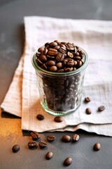 Roasted coffee beans in a small glass jar on a linen napkin
