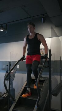 Vertical - muscular man model performing high-intensity cardio on a stair climber machine, focusing on fitness and leg strength at a modern gym.