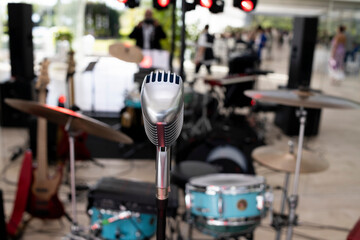 Professional audio equipment. A vintage chrome microphone in the foreground, positioned in the center of a stage ready for a live performance.