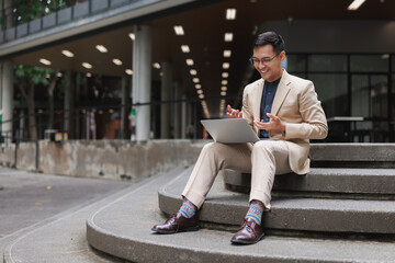 Asian businessman having video call on laptop outdoors