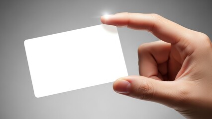 Obraz premium Hand holding a blank white card, finger on top. Studio lighting, grey backdrop