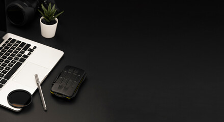 Workspace top view with modern laptop camera and pen on black background with copy space