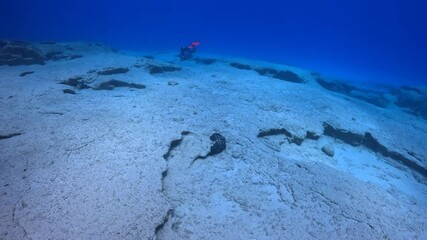 Deep seabed with rock and scuba divers explorers. Underwater video from scuba diving in the ocean, rocks and stones. Sand and stones, travel footage from scuba diving trip. Scuba diver explorer.