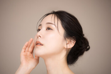 Fototapeta premium 髪の毛がアップ背景がベージュの使いやすい美容やスキンケアの美しい女性のイメージ 見上げる クローズアップ