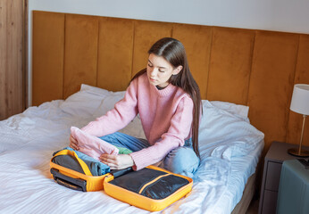Young woman packing clothes in suitcase for travel trip
