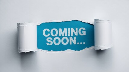 Bright blue paper torn open revealing the words coming soon in white text creating anticipation and excitement for an upcoming event or product launch