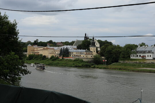 Scenic view of the Vistula River with a tourist boat and the historic Norbertine Monastery in Krakow, Poland
