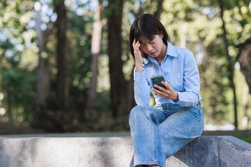 Young woman feeling stressed looking at smartphone screen