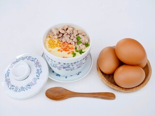 Steamed eggs topped with minced pork, carrots, chopped green onions and fried garlic are served in a steamed egg cup. It looks so delicious and appetizing.