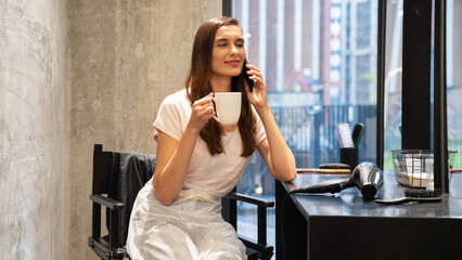 Woman enjoying coffee and talking on the phone in a modern salon during the afternoon