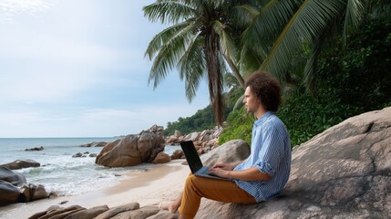 Man is sitting on a rock by the ocean with a laptop. He is wearing glasses. The laptop is open and he is typing