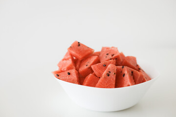 Fresh watermelon slices in a white bowl on white background