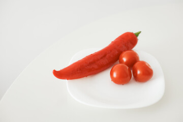Fresh red chili pepper and cherry tomatoes on white plate