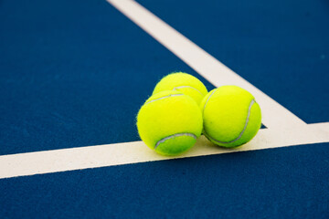 Three yellow tennis balls on blue tennis court © Cavan