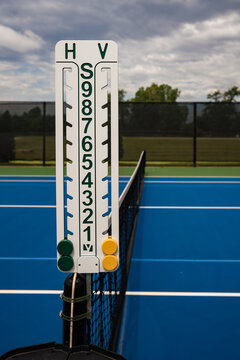 Close-up of tennis court scoreboard mounted on net post.