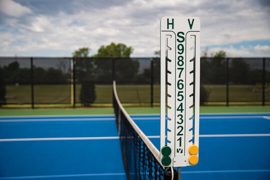 Scoreboard on net of bright blue outdoor tennis court.