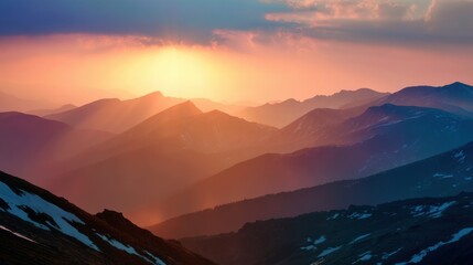 Vibrant colors of a sunset illuminate distant mountain peaks beneath soft clouds. Shadows and light create a stunning view of the natural landscape in the evening.