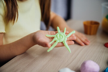 A little girl makes figurines out of colored airy plasticine, modeling dough. Hobbies for children's creativity, educational activities, development of fine motor skills of hands. © Cherkasova Alie