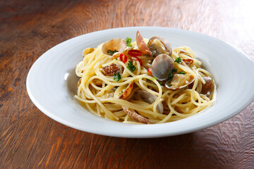 白い器に盛ったボンゴレビアンコ　木目背景