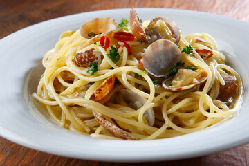 白い器に盛ったボンゴレビアンコ　木目背景