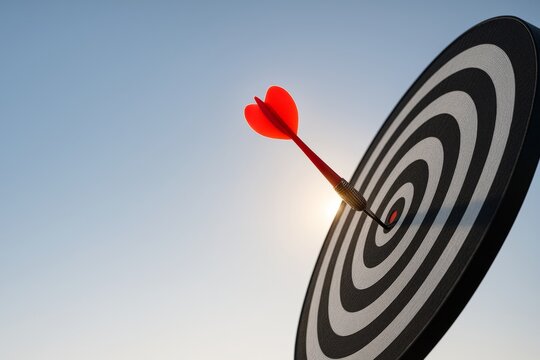 Red dart hitting bullseye on black and white target with sun in background symbolizing precision, achievement and goal success concept. Ai generative