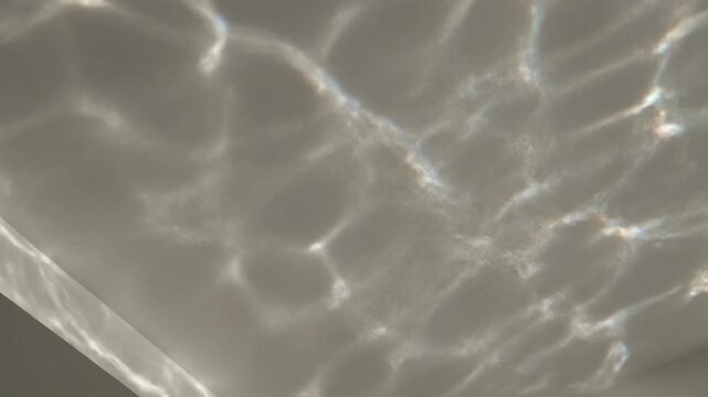 Dynamic caustics pattern of shimmering water ripples reflecting and moving across a clean, neutral indoor ceiling background abstract, neutral indoor ceiling, flow