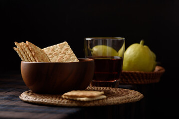 Thin, crispy, slightly salty crackers served with fresh pears and apple cider vinegar on a black background
