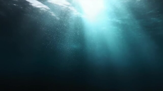 Sunlight beams filter through deep blue ocean water, rays piercing toward the dark depths.