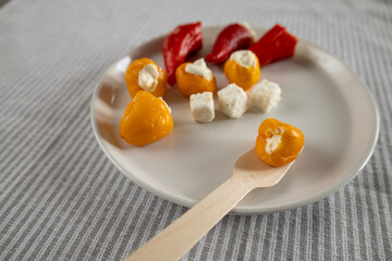 stuffed mini peppers and cheese cubes with wooden fork on plate